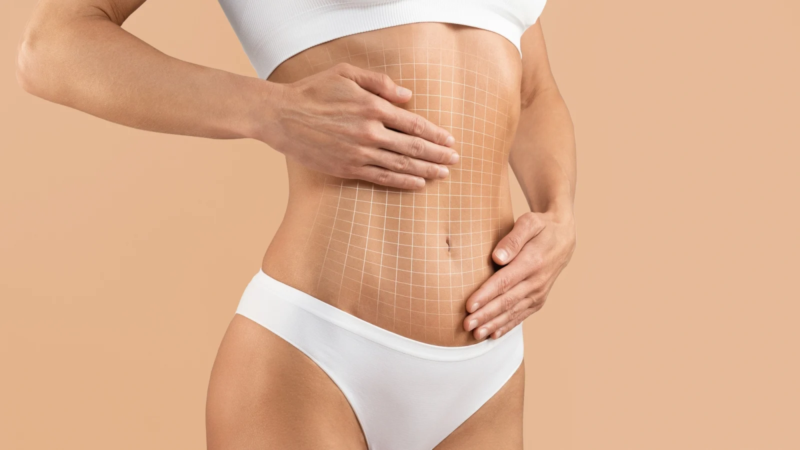 Person's midsection with hands framing the abdomen, marked with a grid overlay against a neutral tan background